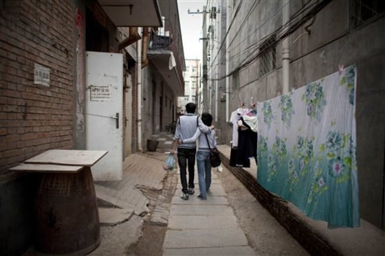 A young couple walk back to their rented room after the day's work at Tang Jialing village where young educated Chinese crowd in shared rooms in Beijing, China.